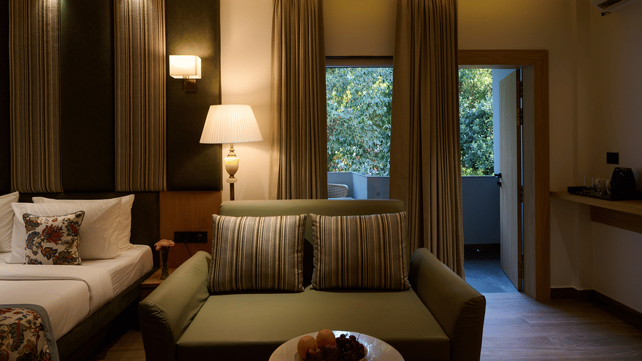 A hotel room focused on a living area with a sofa, a side table with a lamp, and drapes covering large windows leading to the outside | Voyage Eastin Suites