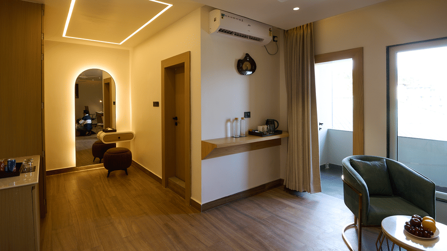 A hotel room or junior suite featuring a curved doorway, a small seating area with a sofa, and a vanity/storage area | Voyage Eastin Suites