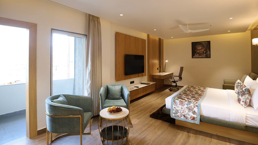 A hotel room with a double bed, a seating area with two armchairs and a small table, and a desk area next to the bed | Voyage Eastin Suites