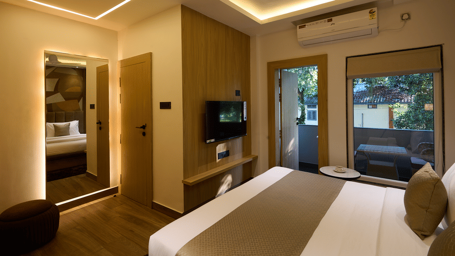 A well-lit room with a neatly made double bed, a wall-mounted TV, and a large window with outdoor views | Voyage Eastin Suites