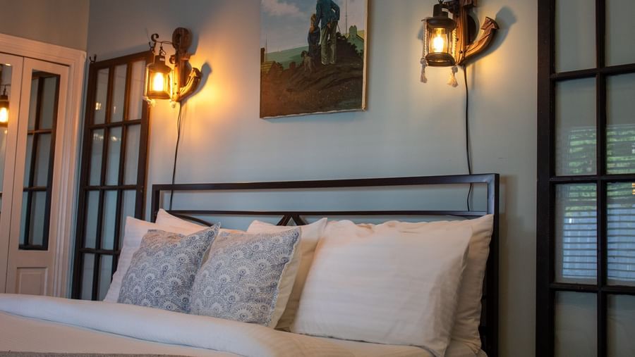 room featuring metal bed frame, lantern lighting, maritime painting and blue accent pillows at Hartstone Inn.