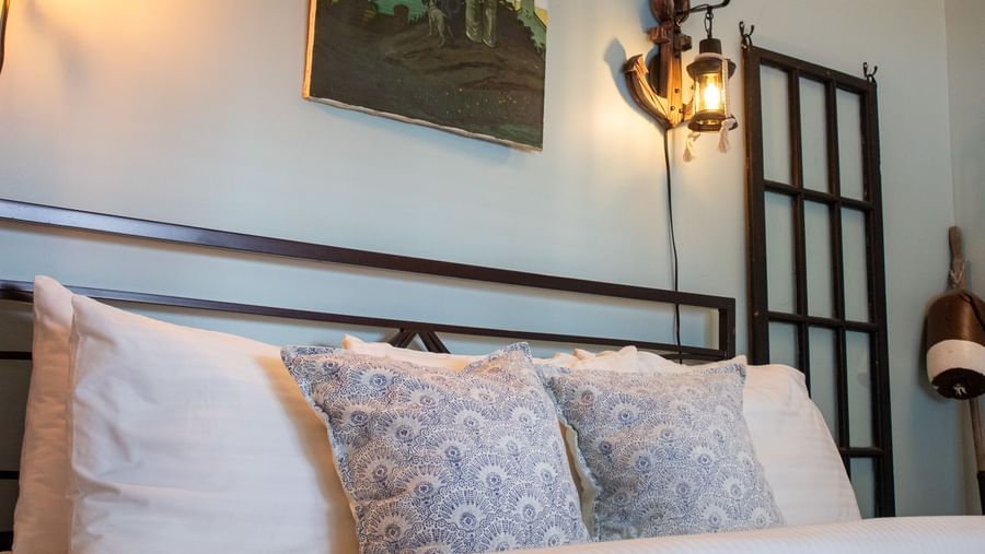 bedroom with metal headboard, blue patterned pillows, maritime artwork and lantern sconces at Hartstone Inn.