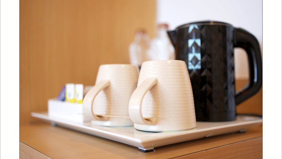 Tea and coffee setup with cups, kettle, and condiments placed neatly on a wooden tray at Mango Grove.
