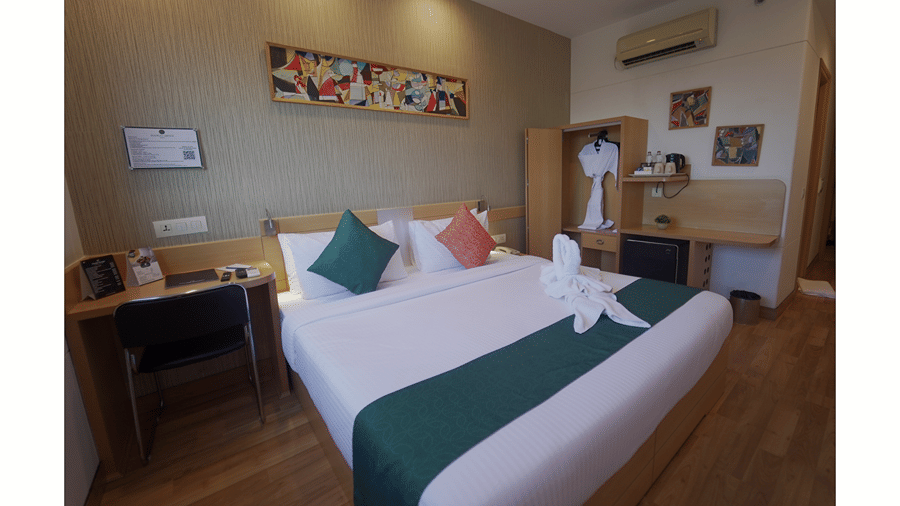 Room with a double bed, green accent wall and framed artwork above the headboard at Mango Grove Hotel.