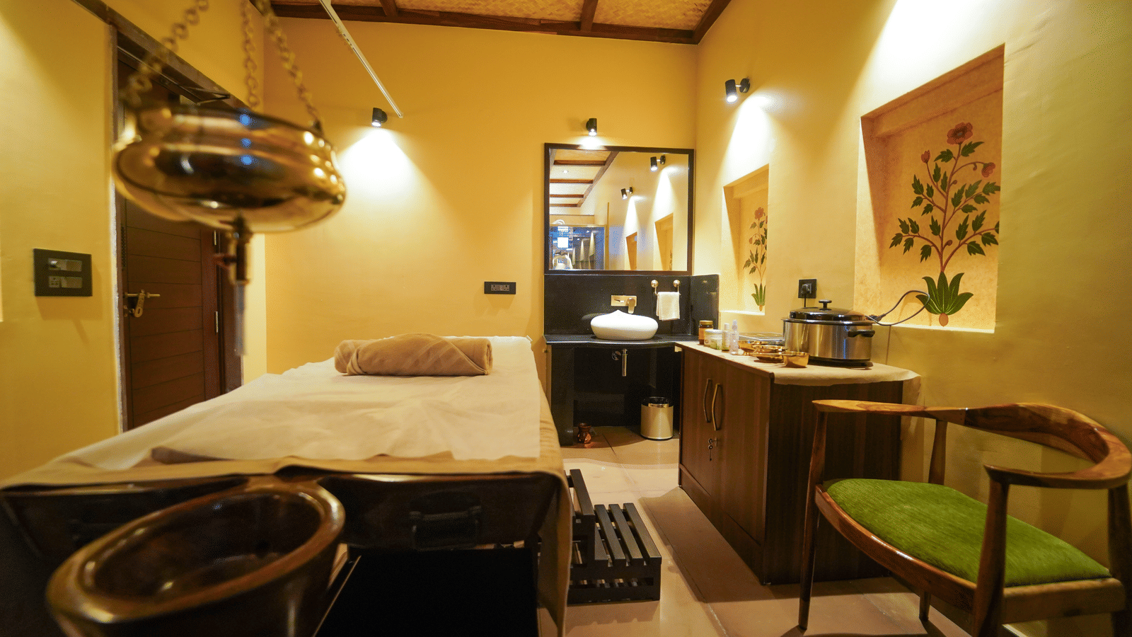 A luxurious wellness setup at Aamaghati Wildlife Resort with a massage bed, Shirodhara pot, and elegant interiors reflecting traditional spa treatments and therapies.