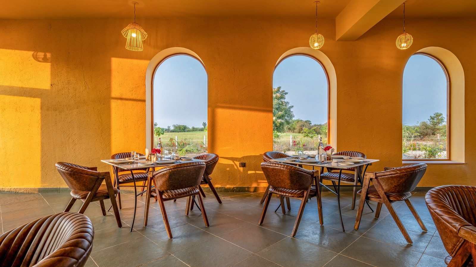 A dining area with neatly arranged chairs around the glass table with mountain view at KURJA Jawai.