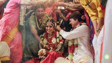 A traditional Indian wedding scene with the bride and groom surrounded by vibrant colours and floral decorations.
