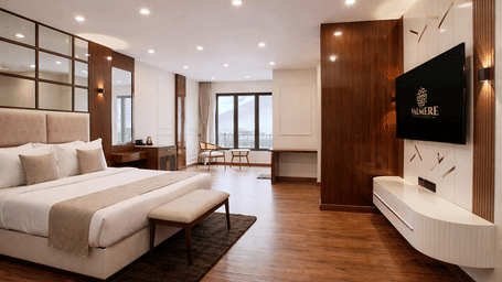 A Junior Suite Room at Valmere Chery Blossom Suites featuring a large bed with a headboard, wooden floors, and large windows with the view outside.