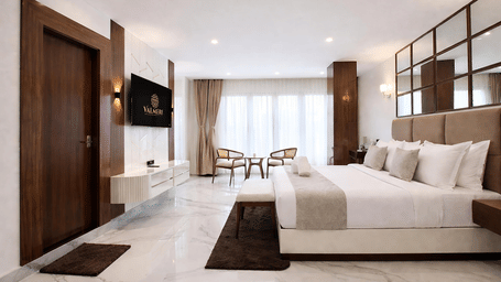 A Premium Triple Room at Valmere Chery Blossom Suites featuring a spacious layout with marble floors, wood-panelled walls, a large bed, and bright natural light.