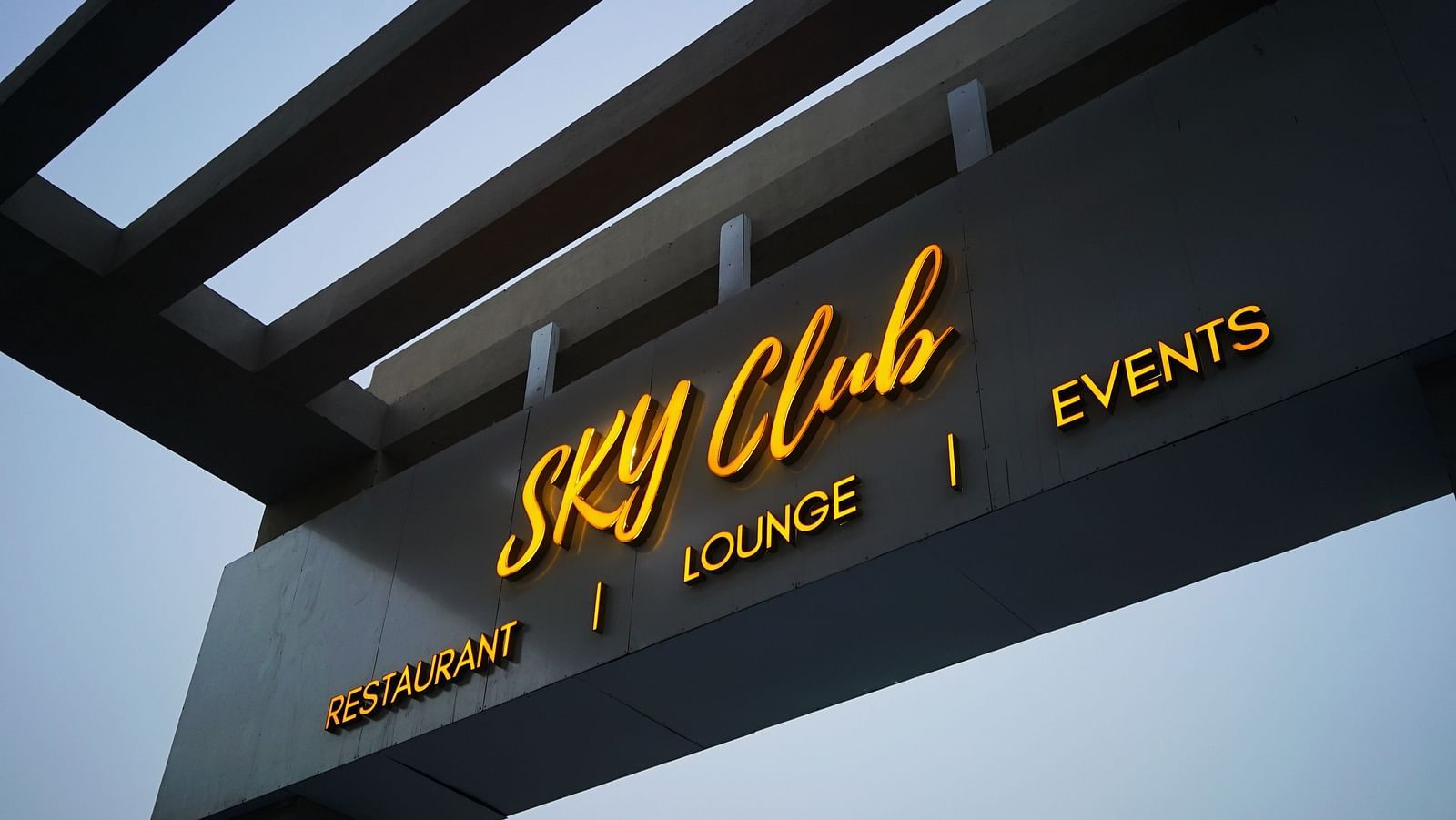A view from below of Sky Club Signage with the sky in the background.