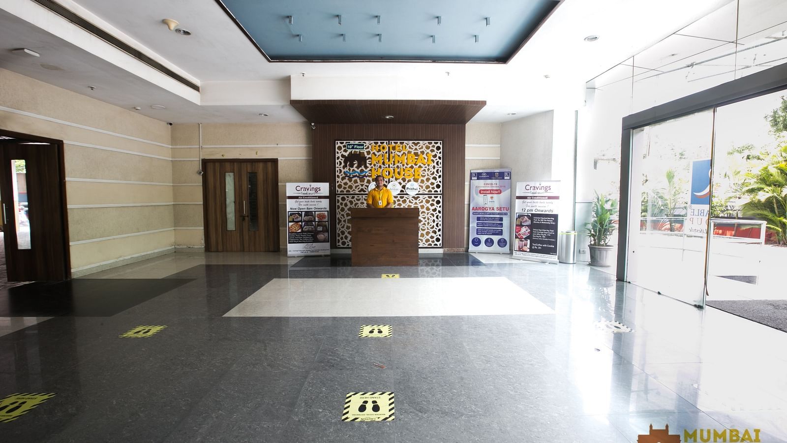 Hotel lobby with a reception desk, social distancing markers and promotional displays.