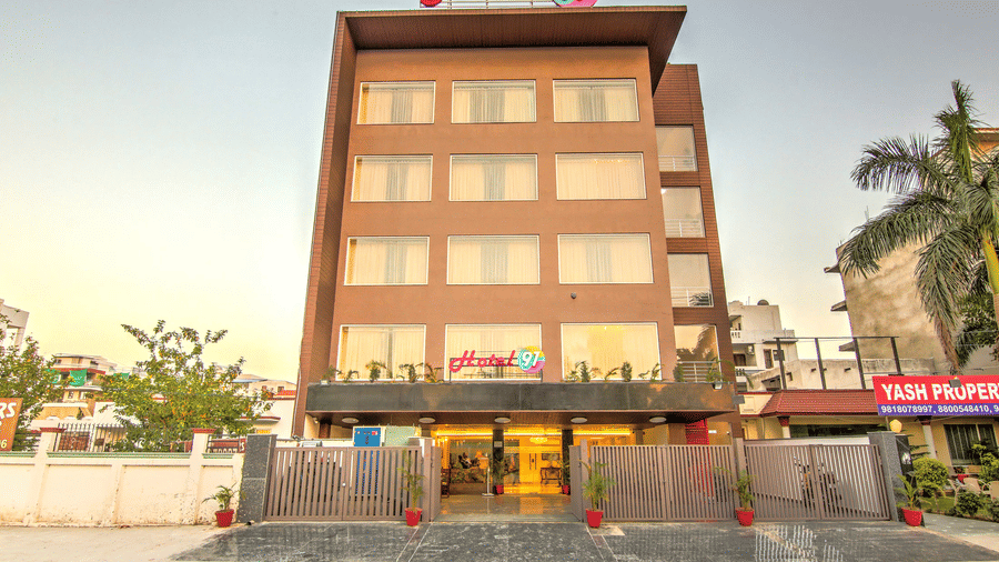 A full frontal view of the multi-storey hotel building featuring a modern brown and glass facade under a bright sky - Hotel 91 HUDA City Centre, Gurugram