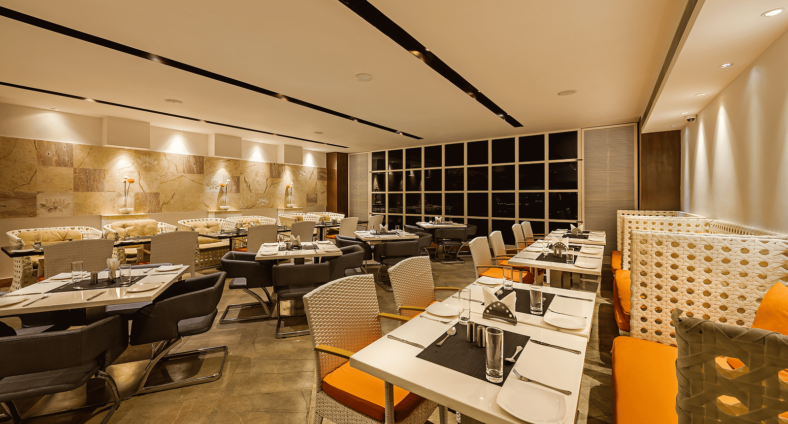 Warm and inviting restaurant dining area with patterned chairs, beige sofas and a neutral color palette - TGI Grand Fortuna, Hosur