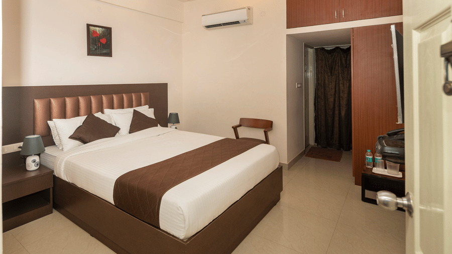 Room at Hotel Bali Nova featuring a double bed with table lamps on both sides on the nightstands and a chair against the wall