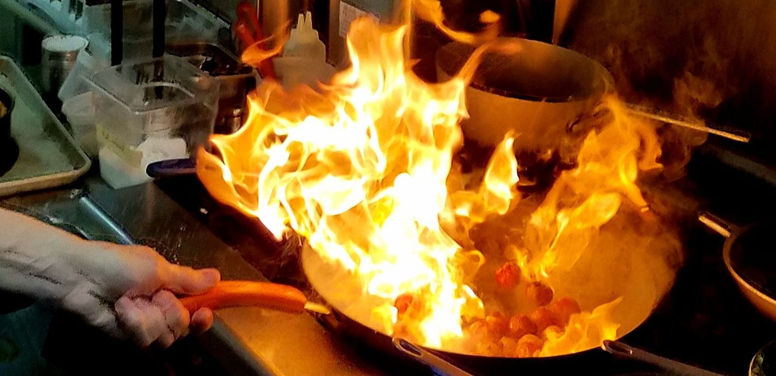 A fiery cooking scene with flames igniting the kitchen - Brewery Gulch Inn & Spa