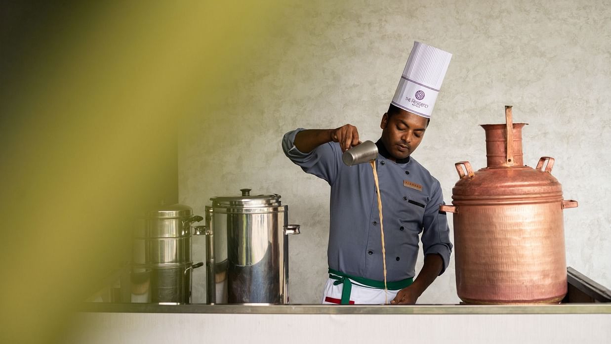 Chef pouring tea in a traditional setting at The Residency Towers