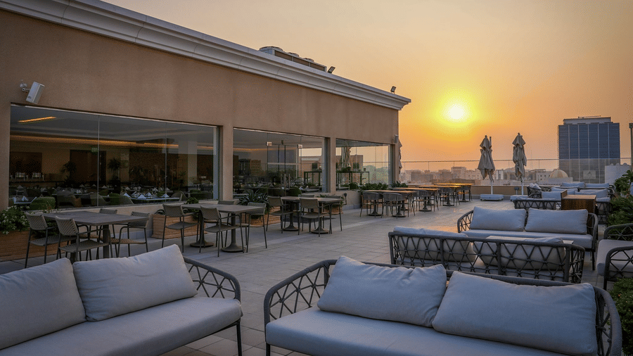 Outdoor terrace seating  with cushioned chairs at La Maison Hotel, Doha during sunset.