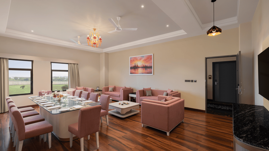 A seating area with sofas, a table, pillows, and windows at Essentia Luxury Hotel and Convention, Nagpur