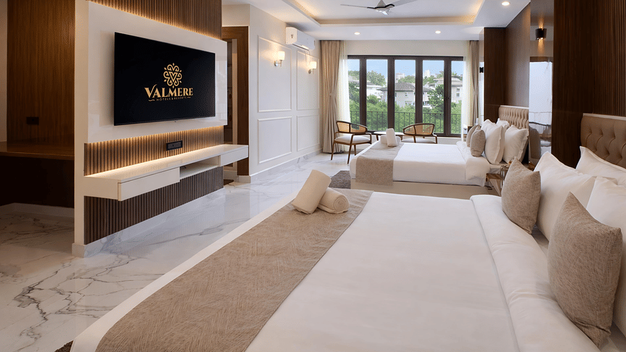 A Family Suite AC Room at Valmere Chery Blossom Suites with 2 plush beds, a flat screen television facing the beds, and a seating area next to large windows.