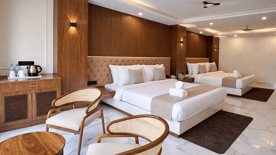 A Family Suite AC Room at Valmere Chery Blossom Suites featuring 2 well-made beds with matching headboards, and a seating area with a round coffee table and 2 chairs.