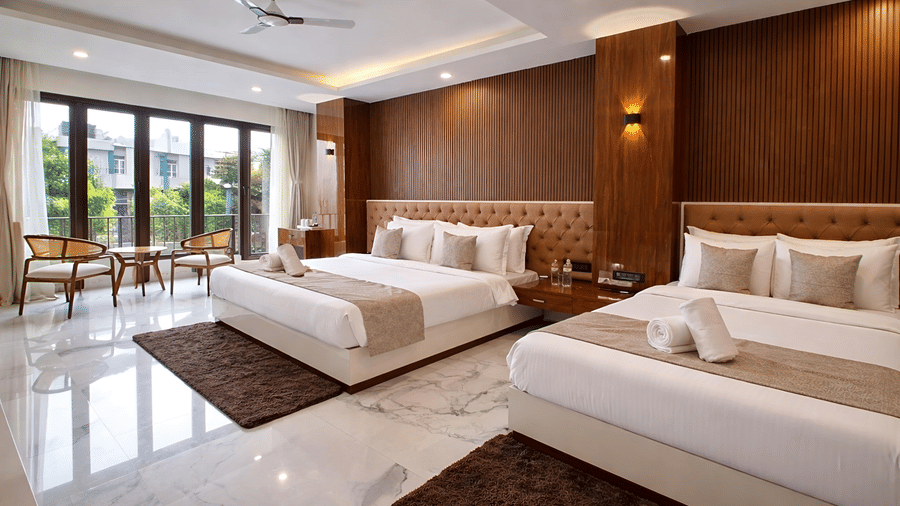 A Family Suite AC Room at Valmere Chery Blossom Suites featuring 2 plush beds, 2 matching rugs, an accent wall with wood panelling, and large windows.