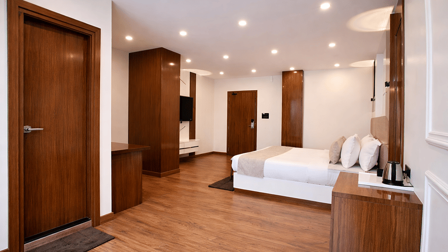 A spacious Junior Suite Room at Valmere Chery Blossom Suites featuring a plush bed, wooden furnishing, and elegant modern lighting.
