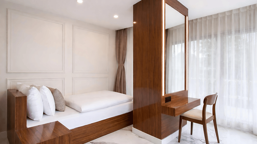 A Premium Triple Room at Valmere Chery Blossom Suites featuring a comfortable single bed next to a wooden vanity desk with a mirror and large window.