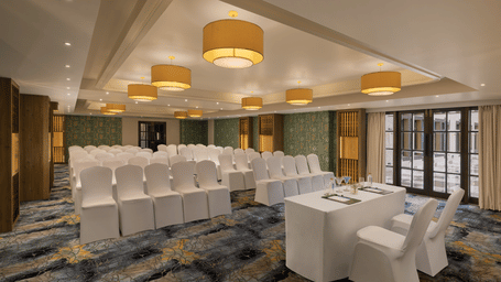 A convention hall with chairs, tables, chandeliers, and carpet. | Essentia Luxury Hotel and Convention, Nagpur
