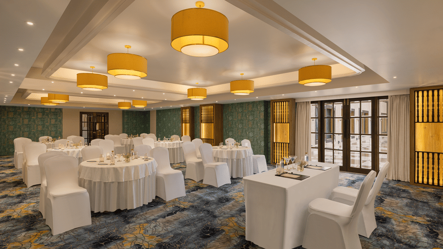 A convention hall with chairs, tables, chandeliers, and carpet. | Essentia Luxury Hotel and Convention, Nagpur