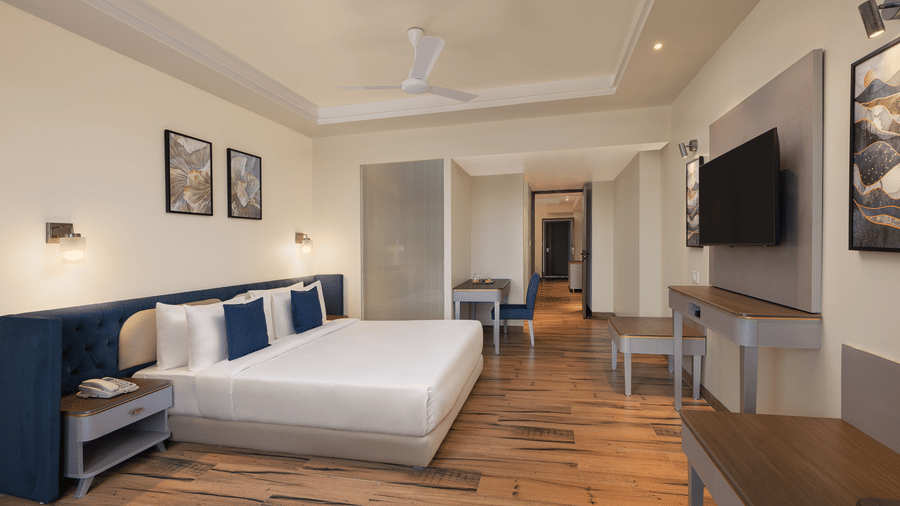 A room with a large bed, spreads, pillows, a television, and wall arts at Essentia Luxury Hotel and Convention, Nagpur