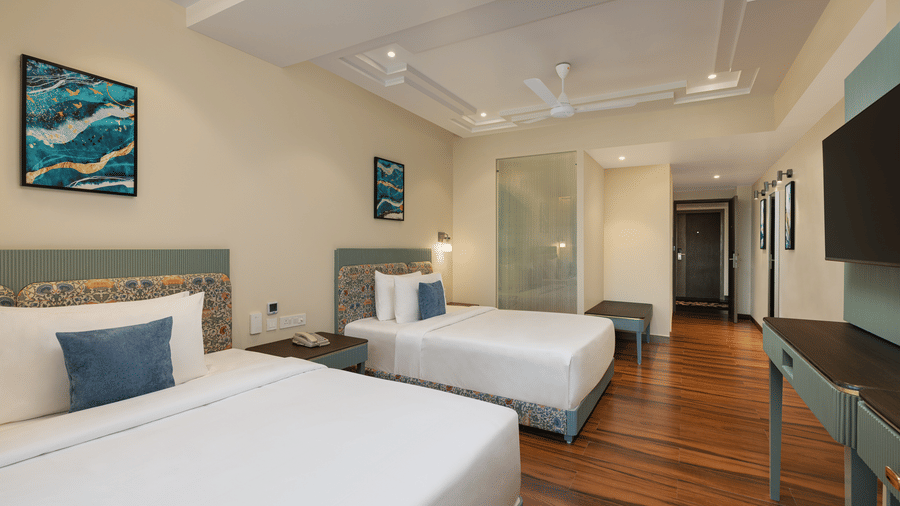 A room with a twin beds, spreads, pillows, a television, and windows at Essentia Luxury Hotel and Convention, Nagpur
