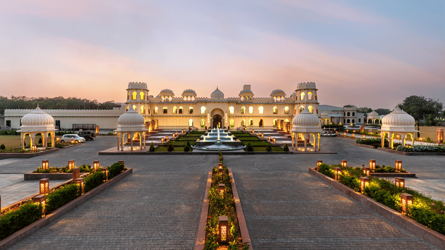 Exterior view of Kesar Bagh Palace building at sunset with landscaped pathways.