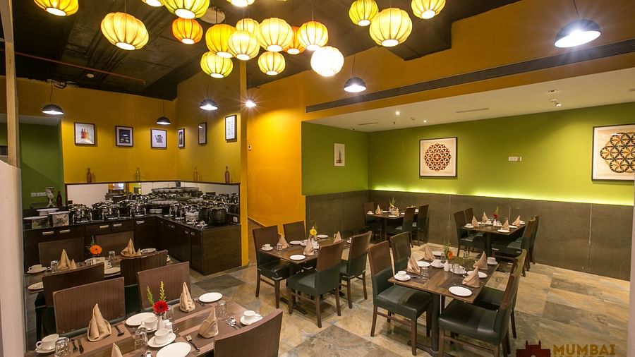 Hotel restaurant with colorful hanging lamps, art-decorated walls, wooden tables, and buffet area.