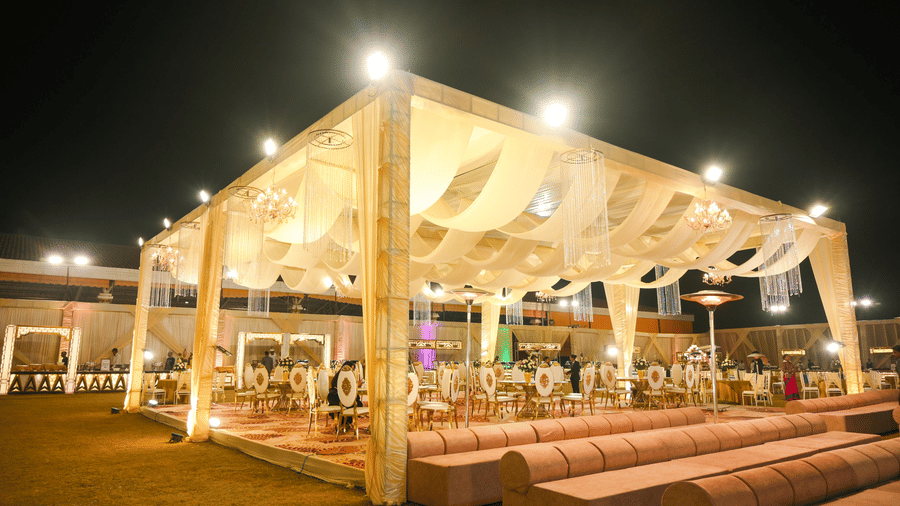 An open pavilion structure with fabric-draped roofing, seating platforms, and open sides arranged around it.