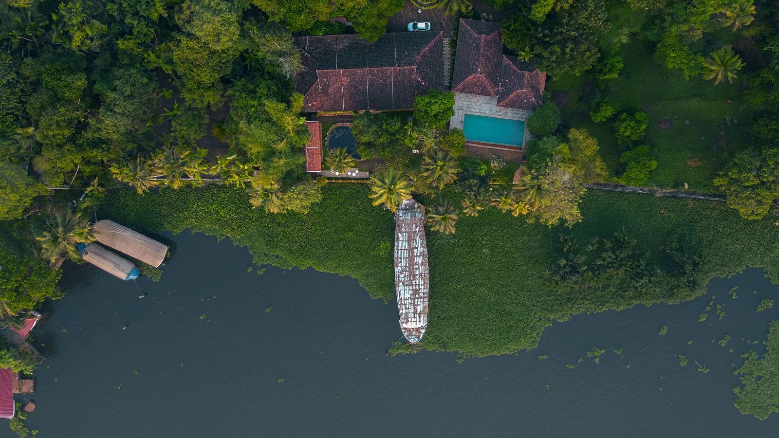 An aerial shot of BluSalzz Villas - Muhamma Resort, Alleppey surrounded by greenery and the Vembanad Lake