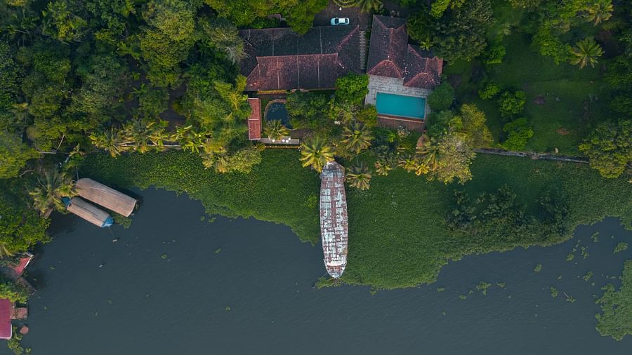 An aerial shot of BluSalzz Villas - Muhamma Resort, Alleppey surrounded by greenery and the Vembanad Lake