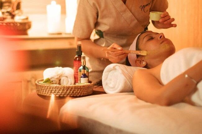 A therapist performing a massage in a warmly lit spa room with candles and flowers at Karma Chalets.