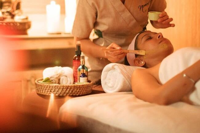 A therapist performing a massage in a warmly lit spa room with candles and flowers at Karma Chalets.