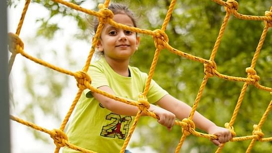 Kid on a commando net ride at inflated trampoline surrounded by trees at Themis Mudhouse - A Nature's Retreat Resort & Wellness