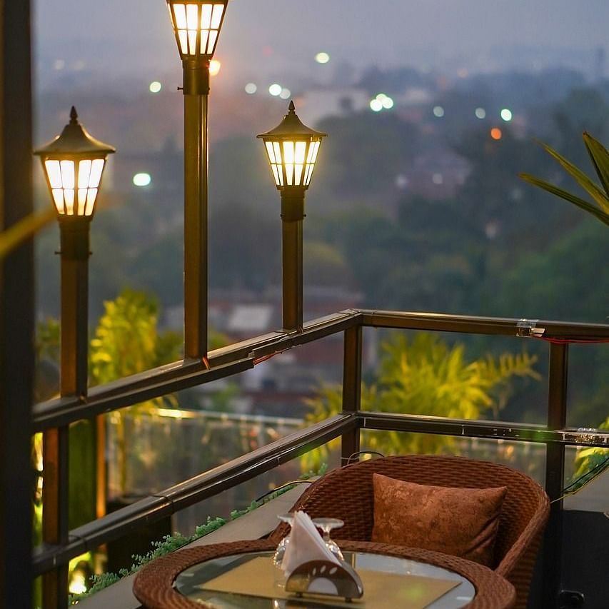 two chairs facing each other on a terrace with warm lights besides it on a late evening