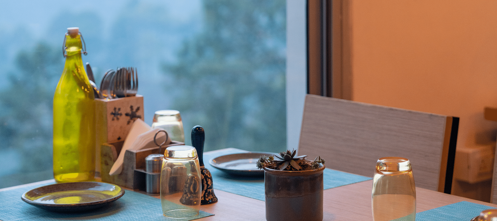 Restaurant table set with a glass bottle and plates at BluSalzz Escapade Resort, Lansdowne.