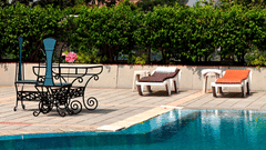 An outdoor swimming pool with sunbeds and scenic views of heritage architecture at a luxury hotel in Lucknow - Clarks Avadh, Luknow