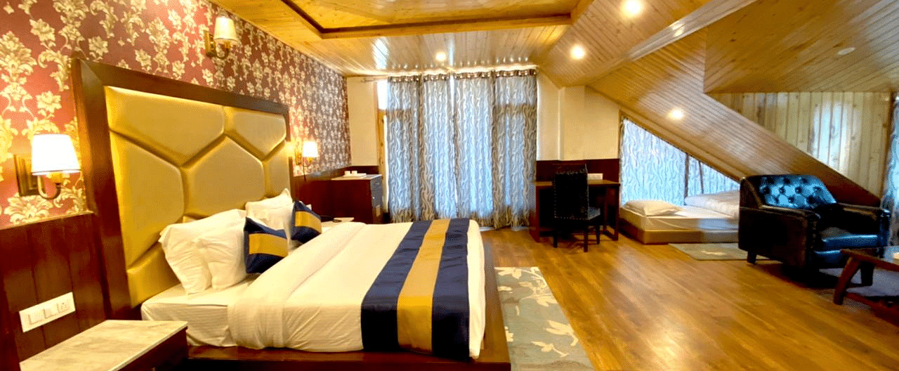 Image of an expansive room with wooden furnishing featuring a double bed and one single bed | DLS La Serene Manali