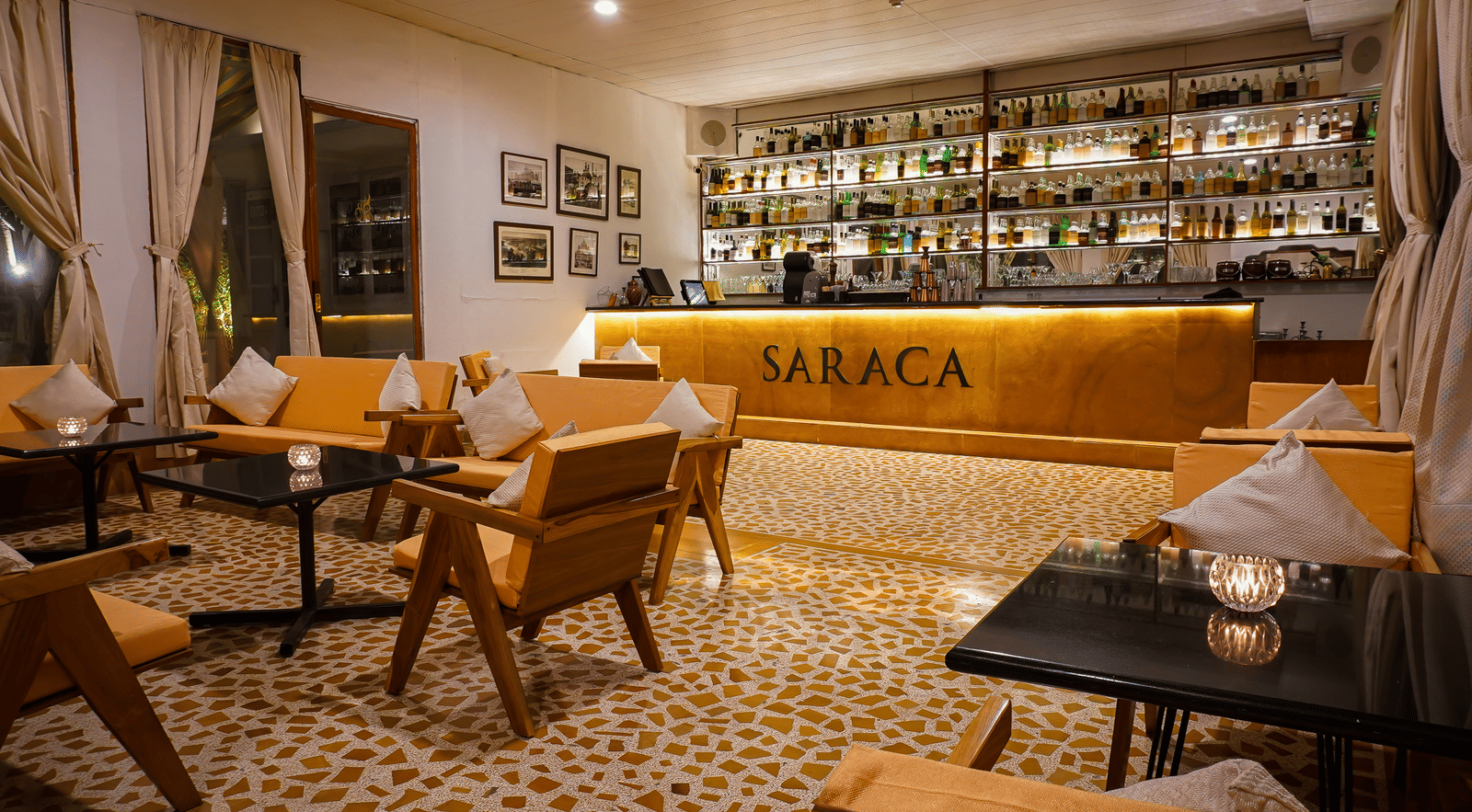 Interior of Saraca Rooftop Lounge at Saraca Hotel, Lucknow, featuring a well-lit bar, wooden seating, and a warm, contemporary ambience ideal for relaxed evening gatherings.