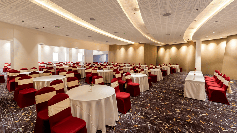 A spacious banquet hall set up with multiple round dining tables and chairs under a curved recessed ceiling at Tiara by MPS.