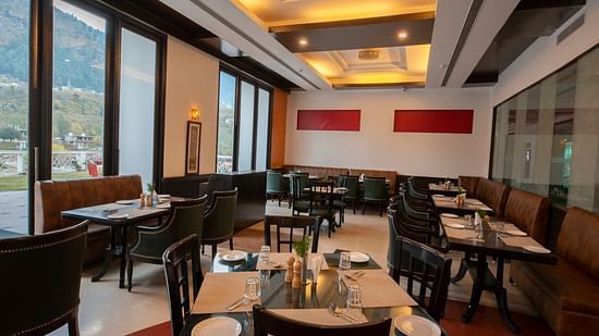 A restaurant with several tables and chairs - Mastiff Grand, Manali