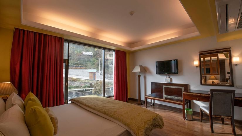 A room with big windows, a TV, a vanity and a tidy bed - Mastiff Grand, Manali