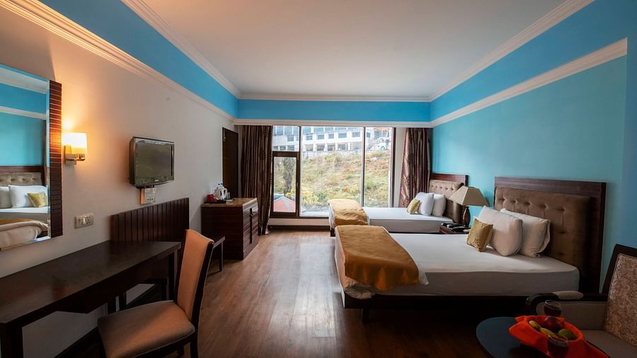 A spacious room with twin beds, a TV, desks, chairs, mirror and a big balcony - Mastiff Grand, Manali