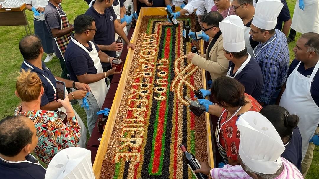 An image of a group of chefs and other people decorating cake with dry fruits in an open field at Cloud9 Sarovar Premiere, Palolem Goa