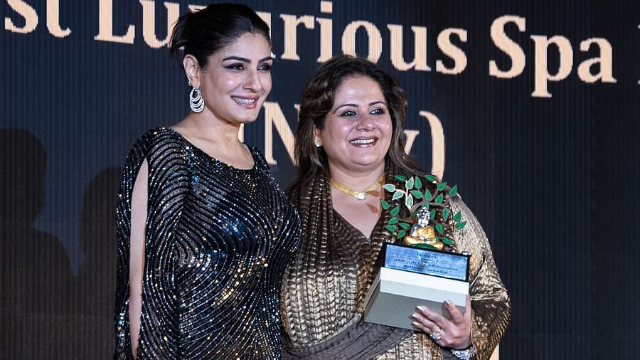 Kiran Bawa being awarded an accolade by a woman at a red carpet event